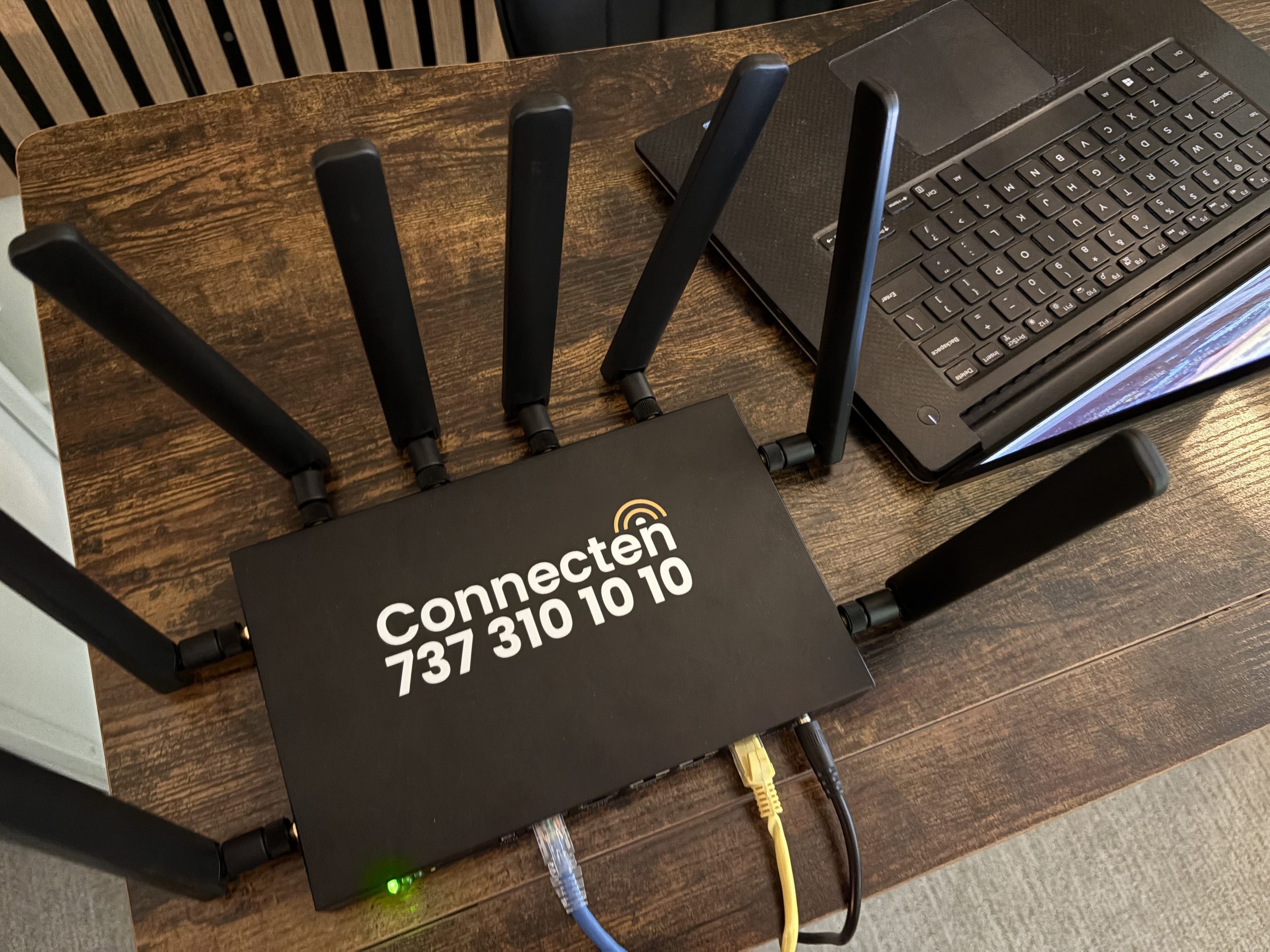 Connecten router top-down view on wood desk with laptop beside it